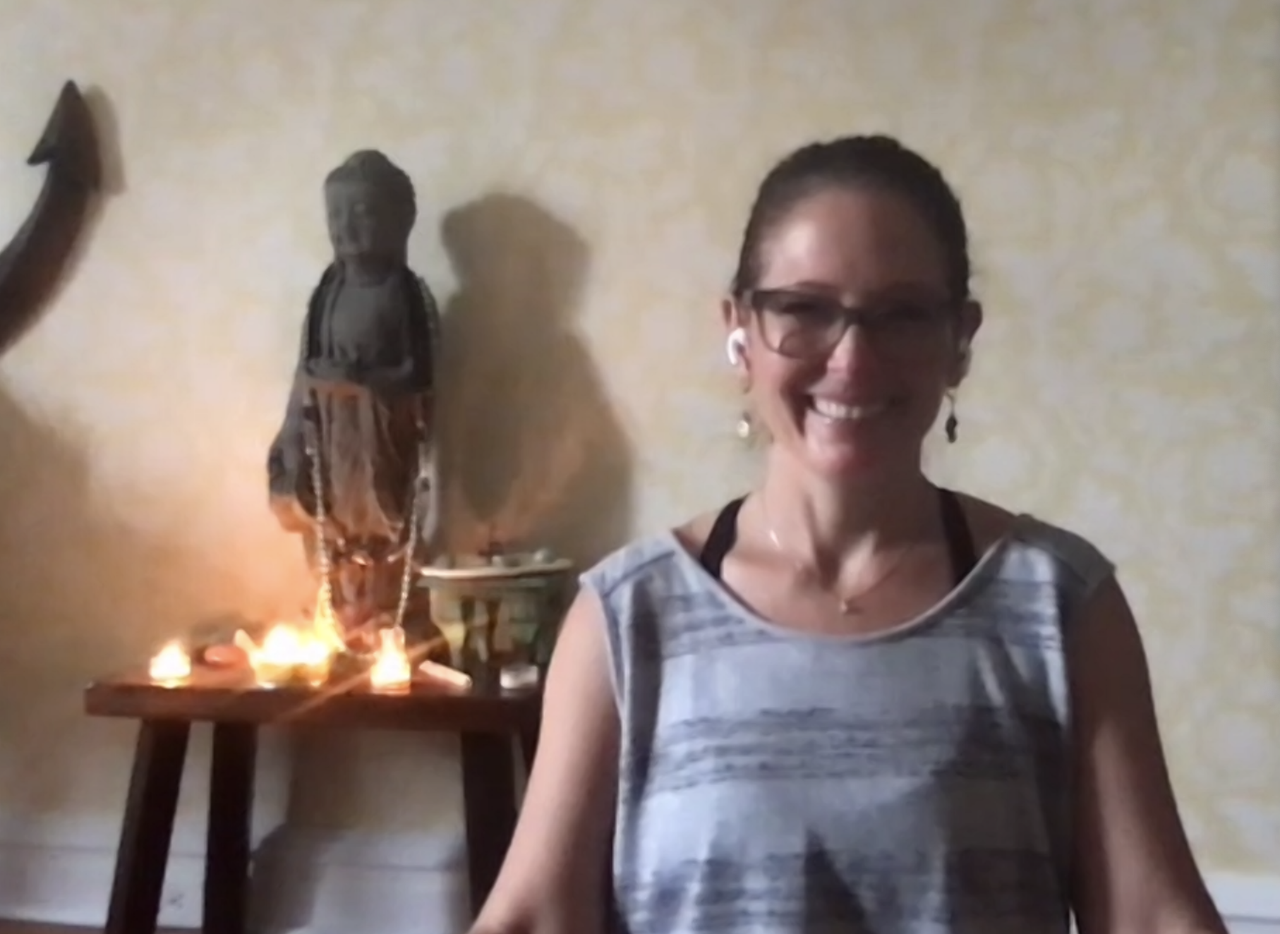 a woman surrounded by candles and a statue leading a guided meditation