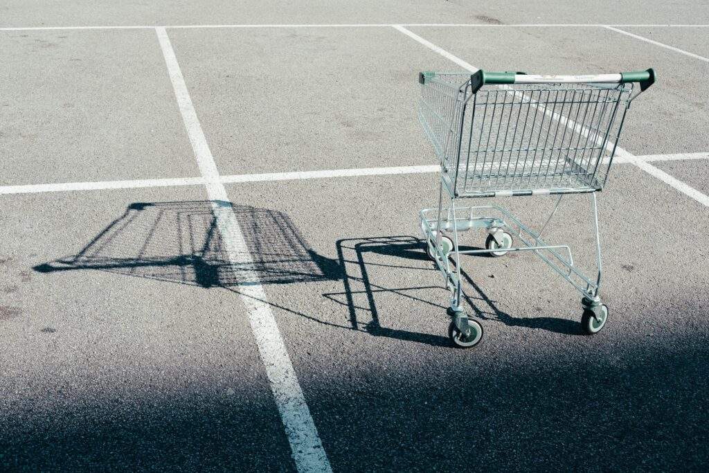 A sad shopping cart left in the middle of a parking lot